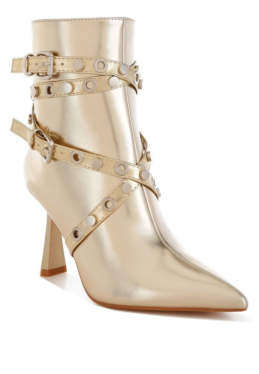 Gold high-heeled boot with studded details on a white background