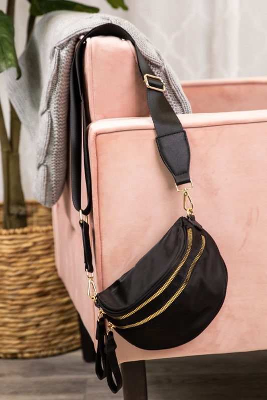 This black crossbody bag features gold zippers and hardware for a touch of elegance.