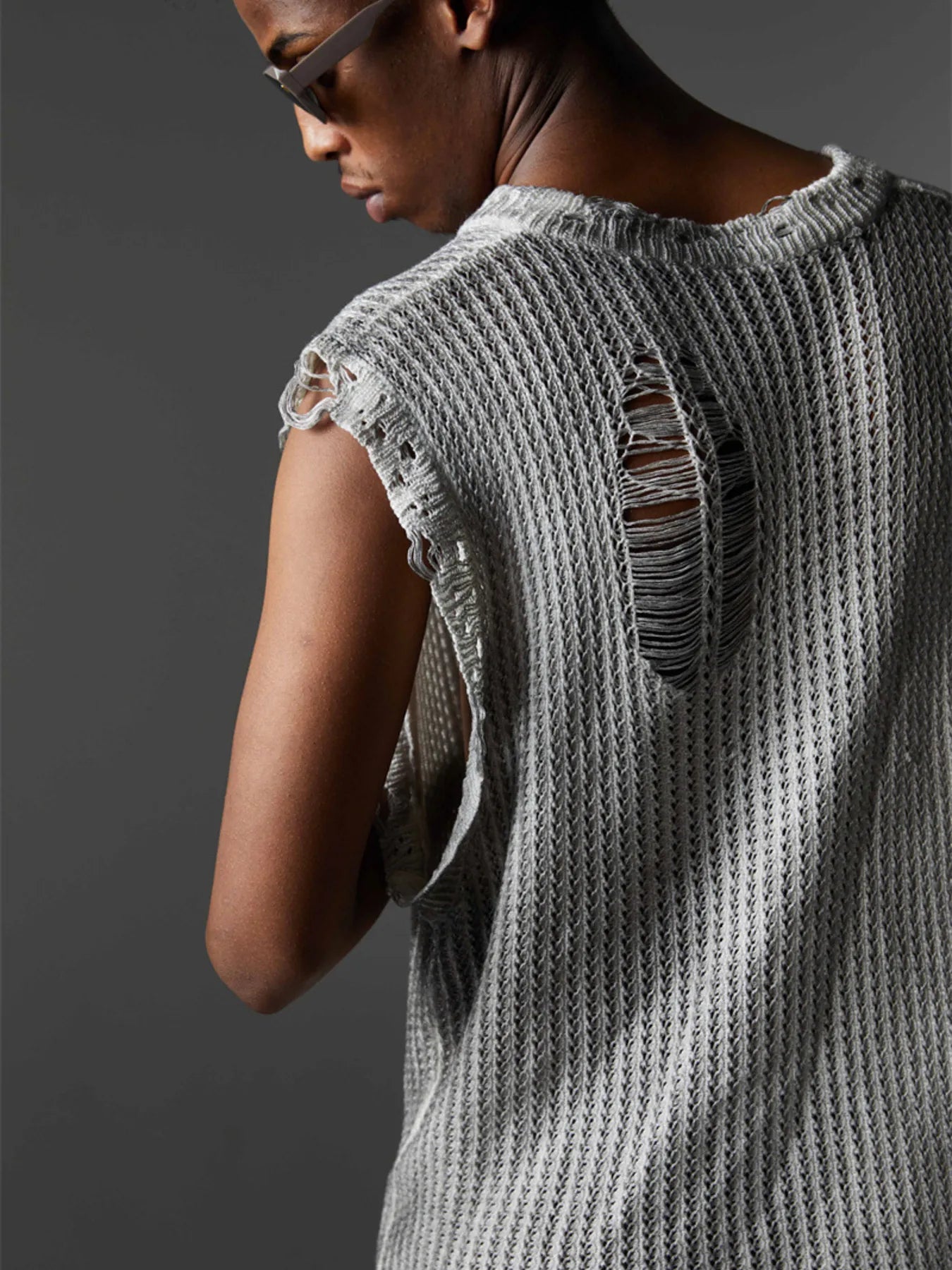A stylish men’s distressed knit vest featuring intentionally frayed edges for a rugged, contemporary look.