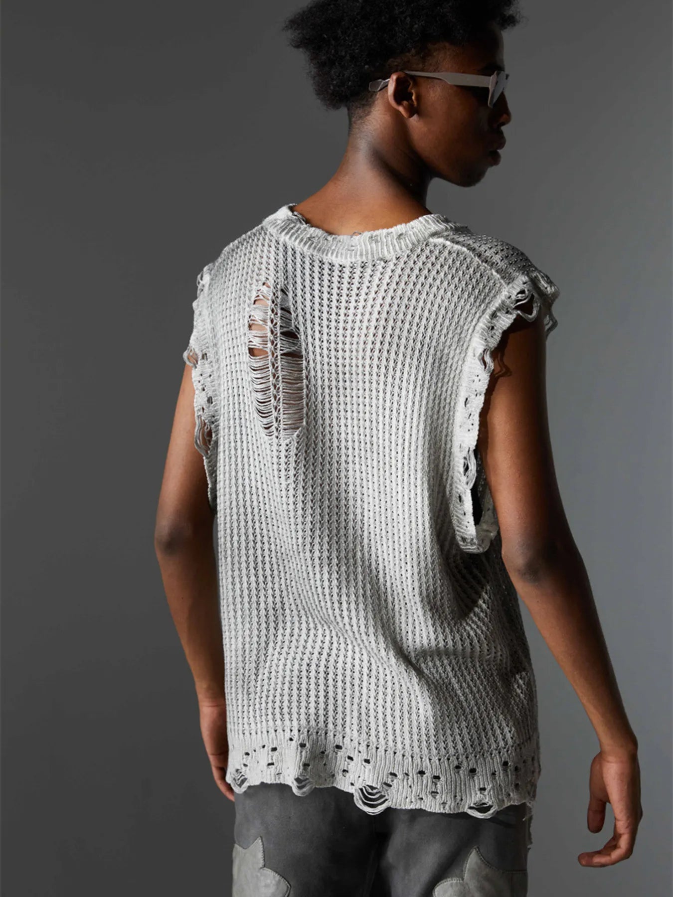 A stylish men’s distressed knit vest featuring intentionally frayed edges for a rugged, contemporary look.