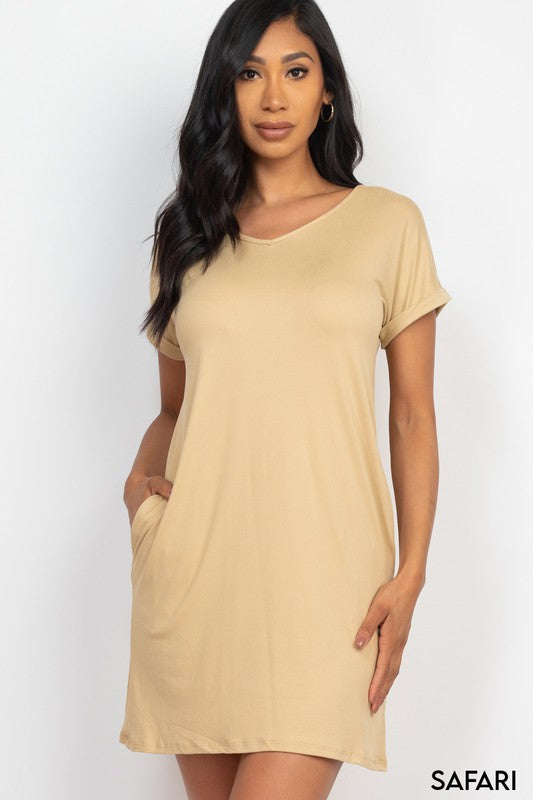 Woman wearing a beige dress with short sleeves and pockets on a white background