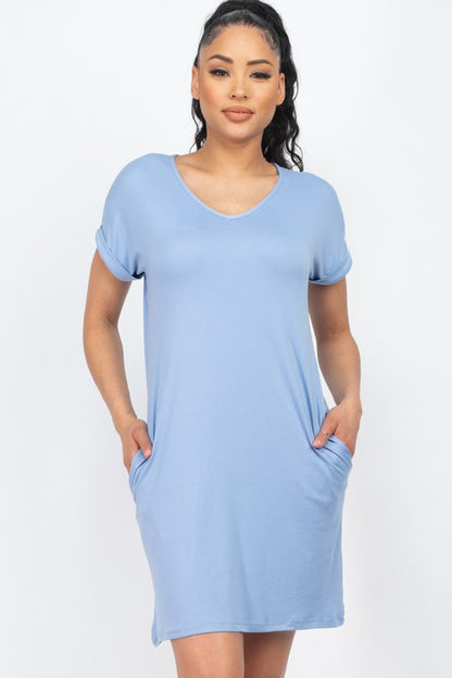 Woman wearing a light blue dress with short sleeves and pockets on a white background