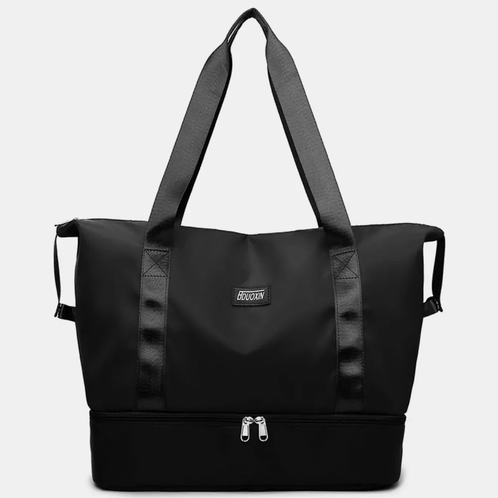 Black tote bag with black handles and dual zippered compartments, set against a soft indoor background. Chic and practical—ideal for gym, travel, or daily use.