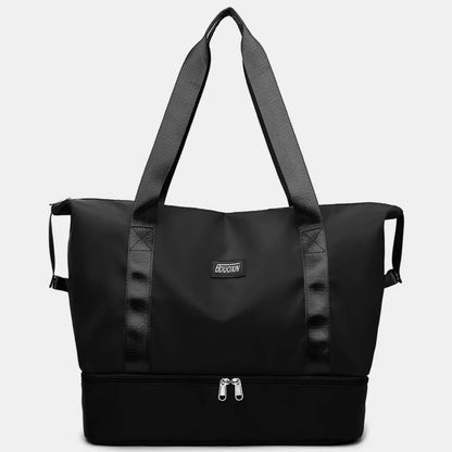 Black tote bag with black handles and dual zippered compartments, set against a soft indoor background. Chic and practical—ideal for gym, travel, or daily use.