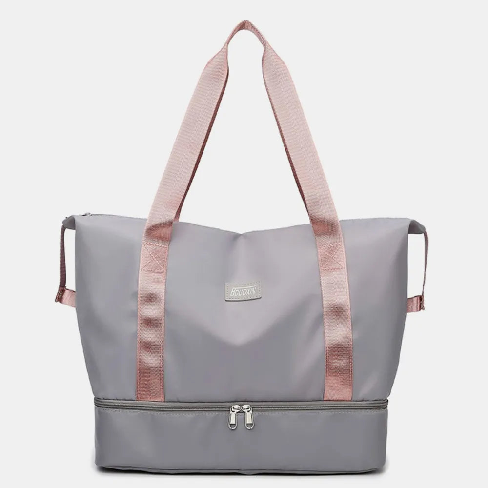 Light gray tote bag with pink handles and dual zippered compartments, set against a soft indoor background. Chic and practical—ideal for gym, travel, or daily use.