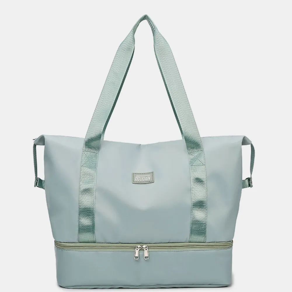 Light blue duffel bags with zippered top and bottom compartments, set against a pastel pink background. Stylish and functional—perfect for travel or gym use.