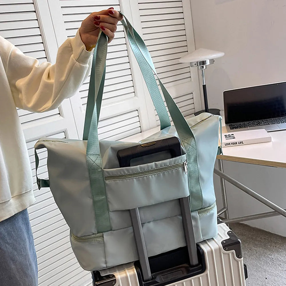 Light blue travel bag with greenish-blue straps, securely placed on a silver suitcase. Convenient sleeve design for easy transport—perfect for organized travel.