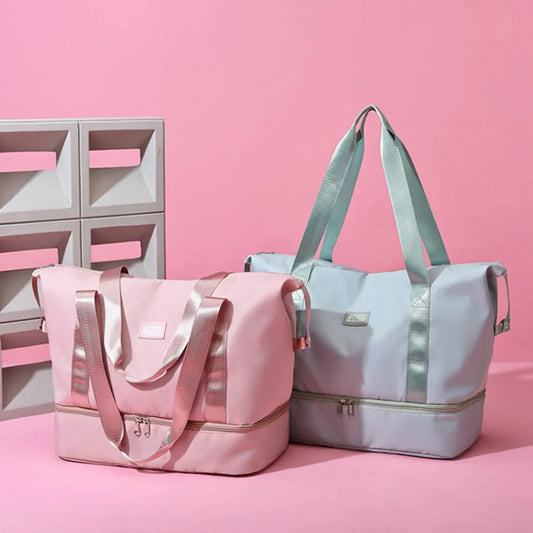 Pink and light blue duffel bags with zippered top and bottom compartments, set against a pastel pink background. Stylish and functional—perfect for travel or gym use.