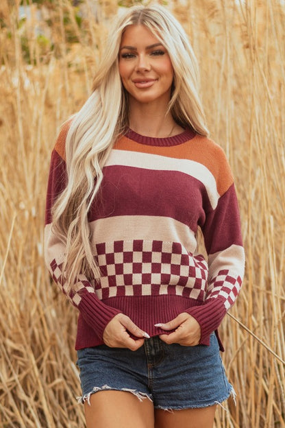  Woman models a checkered color block sweater, featuring a crew neck, perfect for a cozy and stylish look.