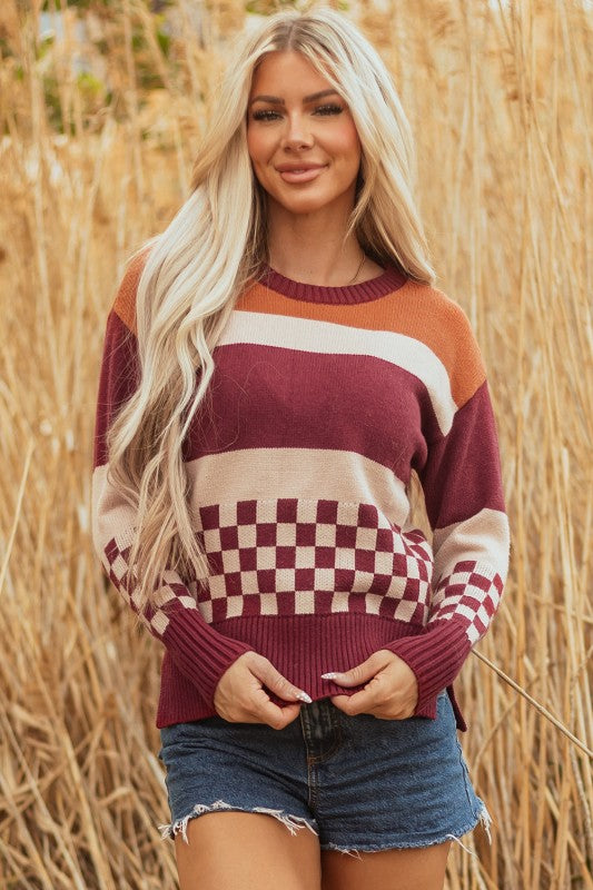  Woman models a checkered color block sweater, featuring a crew neck, perfect for a cozy and stylish look.