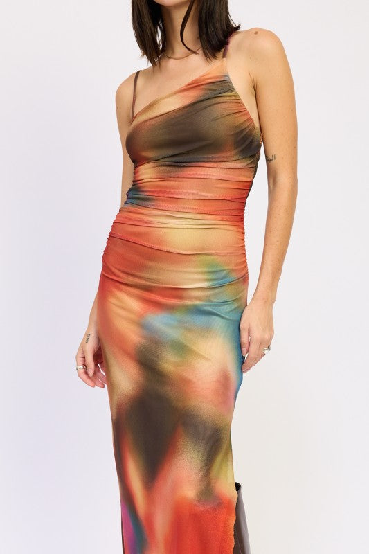 A woman wearing a vibrant, multicolored one-shoulder maxi dress with brown boots, posing against a plain white background.