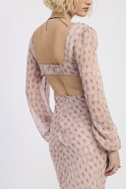 A woman with short blonde hair wearing a pink dress with a pattern and brown boots.