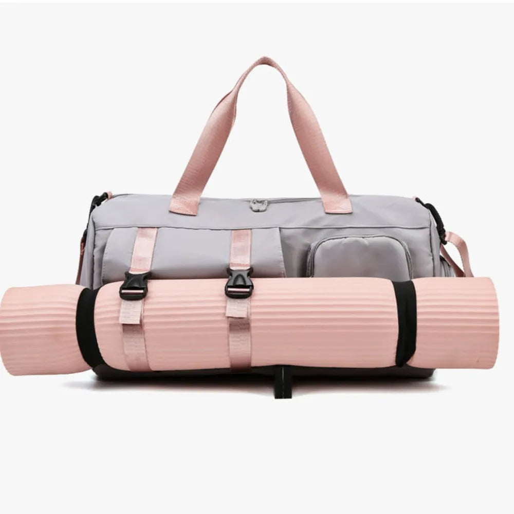 Light gray gym or travel bag with pink handles, featuring a front zip pocket and side compartments. A pink yoga mat is securely attached to the front with black straps—stylish and functional for active lifestyles.