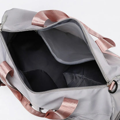 Light gray duffel bag with pink handles and shoulder strap, featuring a front zip pocket and smooth, slightly glossy material. Modern and functional—ideal for gym, travel, or everyday use.