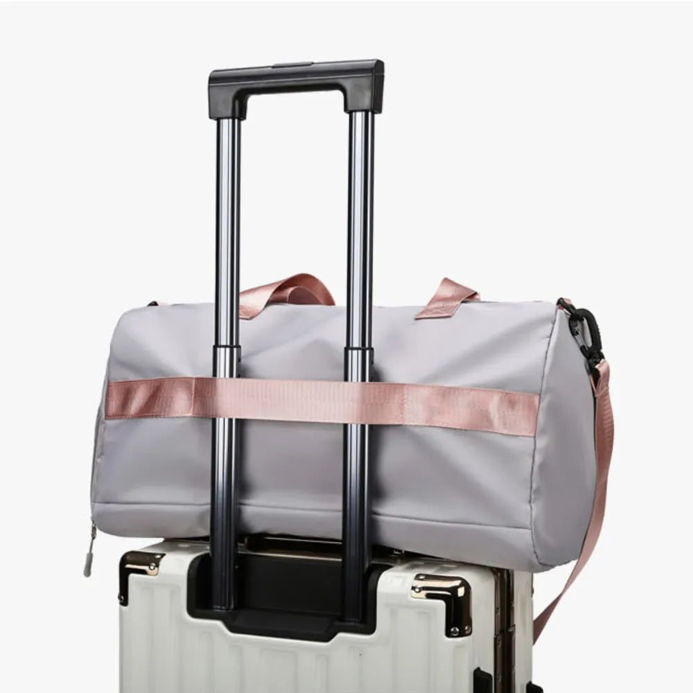 White hard-shell suitcase with telescopic handle paired with a light gray duffel bag featuring pink straps, securely mounted on top—compact and efficient travel setup.