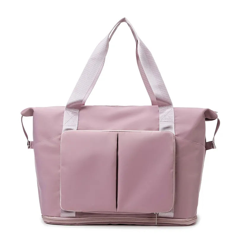 Light pink tote bag with dual shoulder straps, vertical front pockets, and a bottom zip compartment. Made from smooth, water-resistant material with side adjustment straps—stylish and practical for daily use or travel.