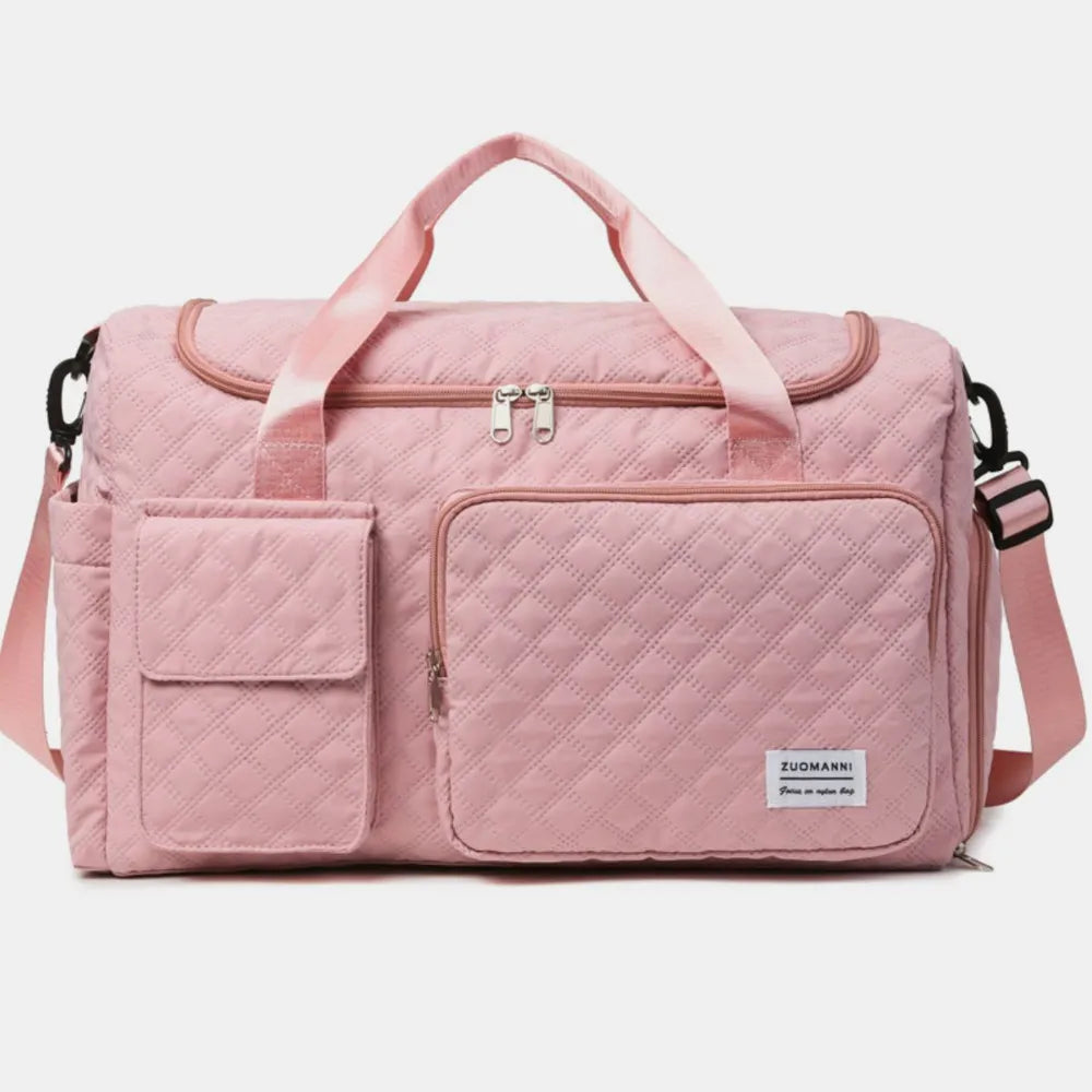 Pink quilted duffel bag with pink straps, featuring a zip pocket and flap pocket on the front. Stylish and functional for travel or gym use.