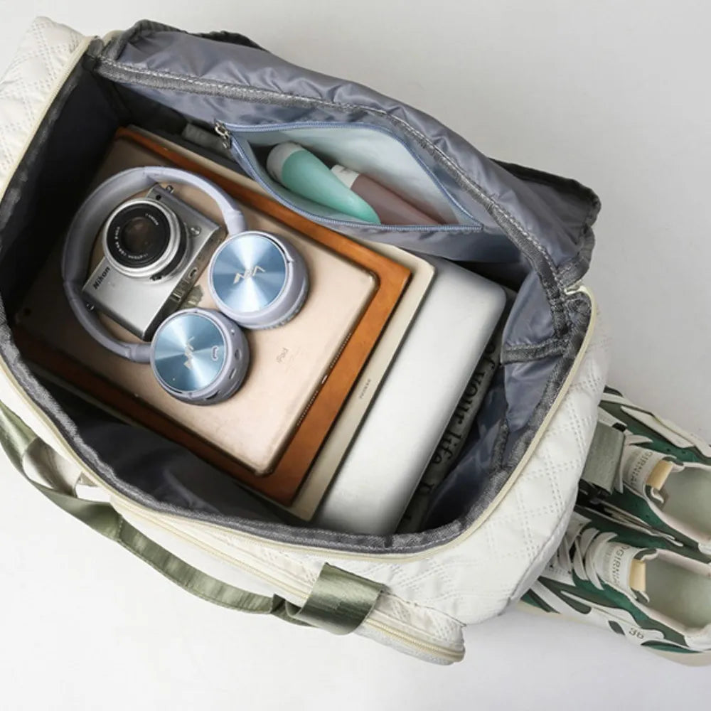 Open white and green duffel bag neatly packed with daily essentials: laptop, tablet, headphones, camera, notebook, water bottle, and sneakers. Clean, organized setup—ideal for travel or everyday use.