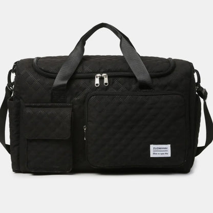 Black quilted duffel bag with black straps, featuring a zip pocket and flap pocket on the front. Stylish and functional for travel or gym use.