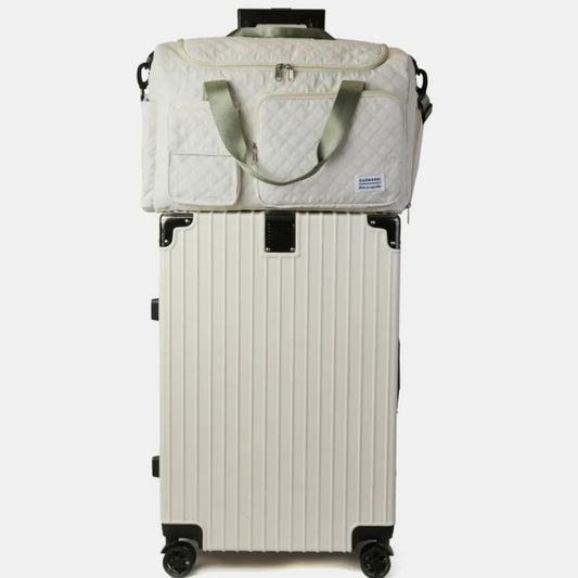 Compact travel setup with a ribbed hard-shell suitcase and a quilted duffel bag featuring green handles and shoulder strap.