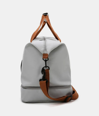 Light gray duffel bag with brown and black straps, featuring a zippered top compartment and an additional bottom section. Sleek and functional—ideal for gym, travel, or everyday use.