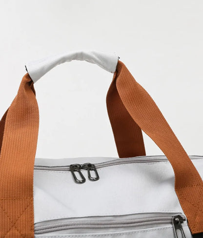 Light gray duffel bag with brown and black straps, featuring a zippered top compartment and an additional bottom section. Sleek and functional—ideal for gym, travel, or everyday use.