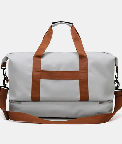 Light gray duffel bag with brown and black straps, featuring a zippered top compartment and an additional bottom section. Sleek and functional—ideal for gym, travel, or everyday use.