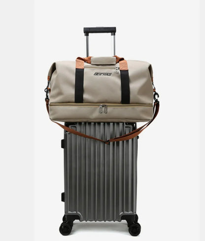 Beige duffel bag with brown accents and a shoulder strap, securely placed on top of a silver hard-shell suitcase with a retractable handle. Compact and convenient setup—perfect for organized travel.