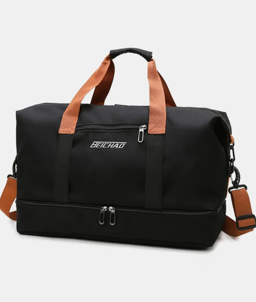 Black duffel bag with orange handles and black vertical straps, featuring a zippered bottom compartment and front pocket label. Bold and functional—ideal for travel, gym, or everyday use.