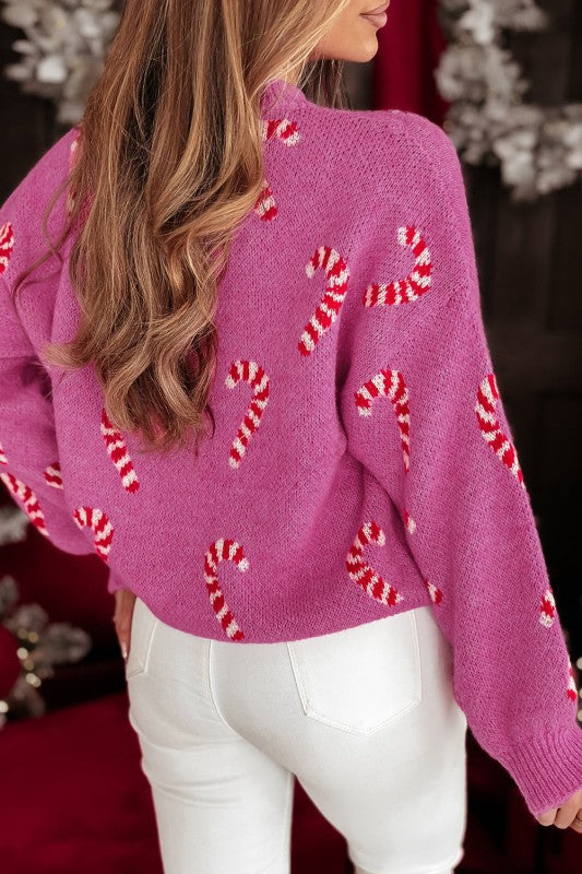 Woman wearing pink candy cane sweater with white pants