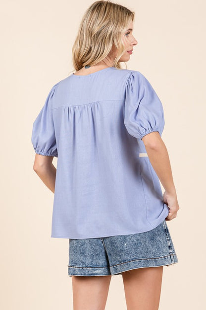 The piped edges contrast beautifully against the flowing body of the blouse.