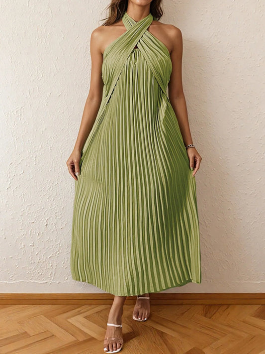 Woman wearing a pleated halter neck midi dress with crisscross neckline.
