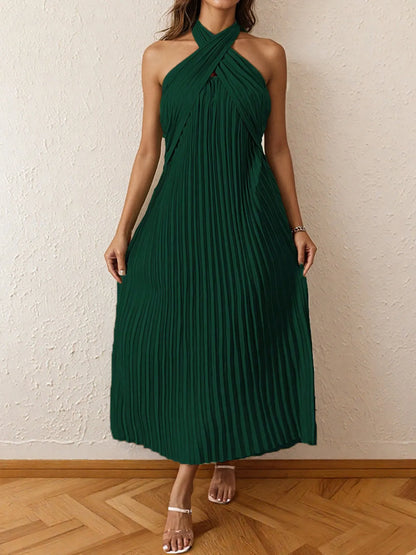 Woman wearing a pleated halter neck midi dress with crisscross neckline..