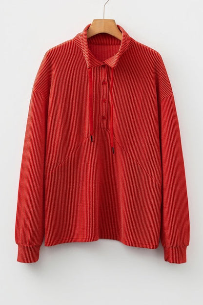 Red ribbed knit sweater with collar and button details on hanger against white background