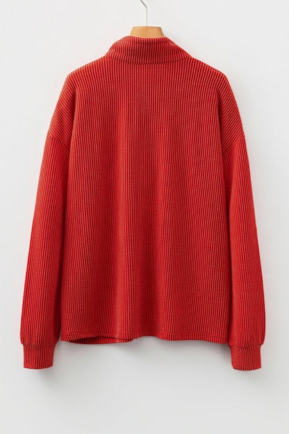 Red ribbed knit pullover with collar displayed on wooden hanger against white backdrop