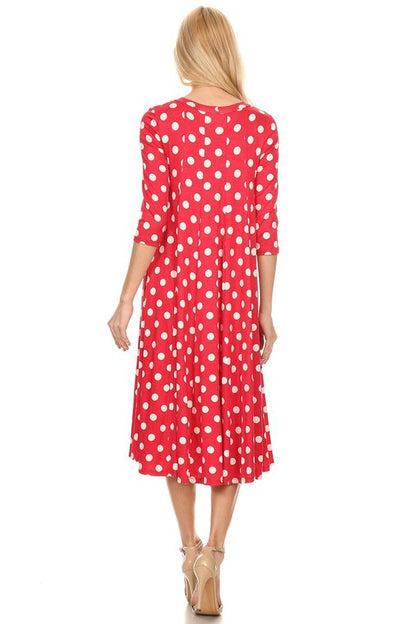 Woman wearing a paneled polka dot A-line midi dress with ¾ sleeves.