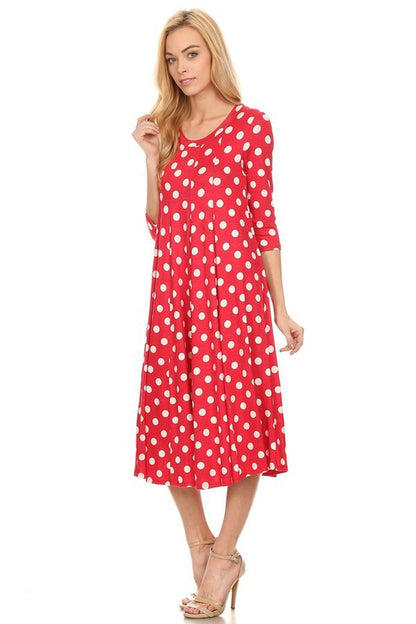 Woman wearing a paneled polka dot A-line midi dress with ¾ sleeves.