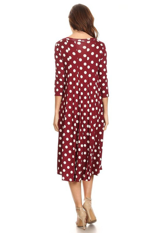 Woman wearing a paneled polka dot A-line midi dress with ¾ sleeves.
