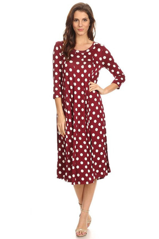 Woman wearing a paneled polka dot A-line midi dress with ¾ sleeves.