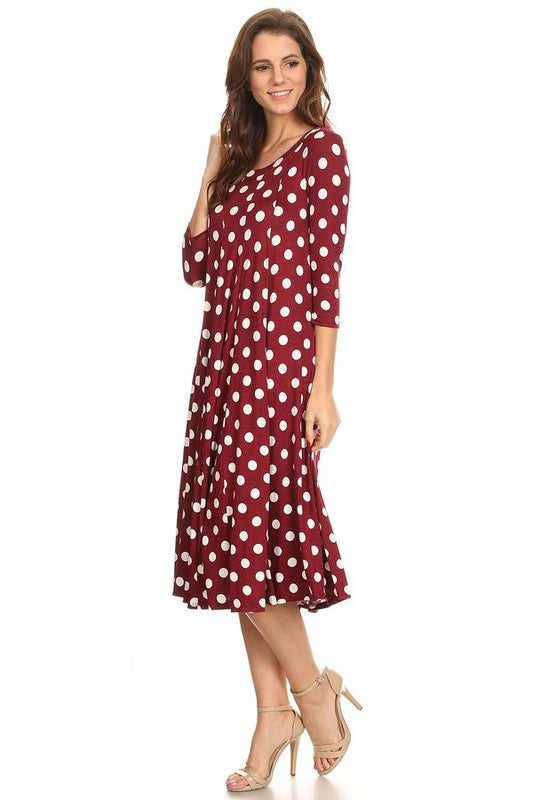 Woman wearing a paneled polka dot A-line midi dress with ¾ sleeves.