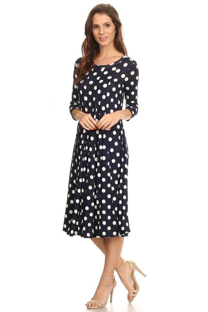Woman wearing a paneled polka dot A-line midi dress with ¾ sleeves.