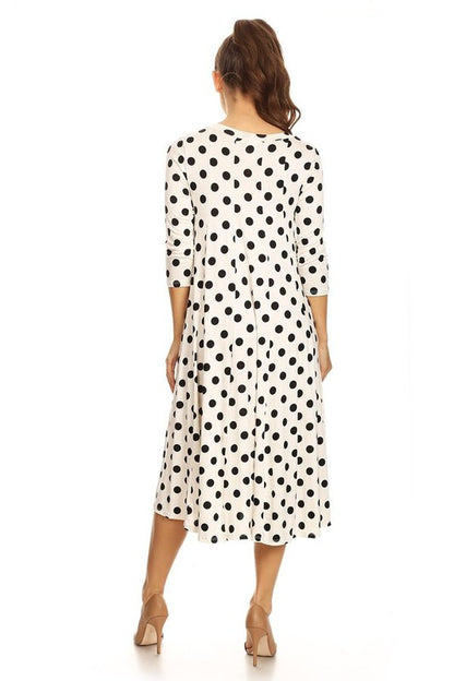 Woman wearing a paneled polka dot A-line midi dress with ¾ sleeves.