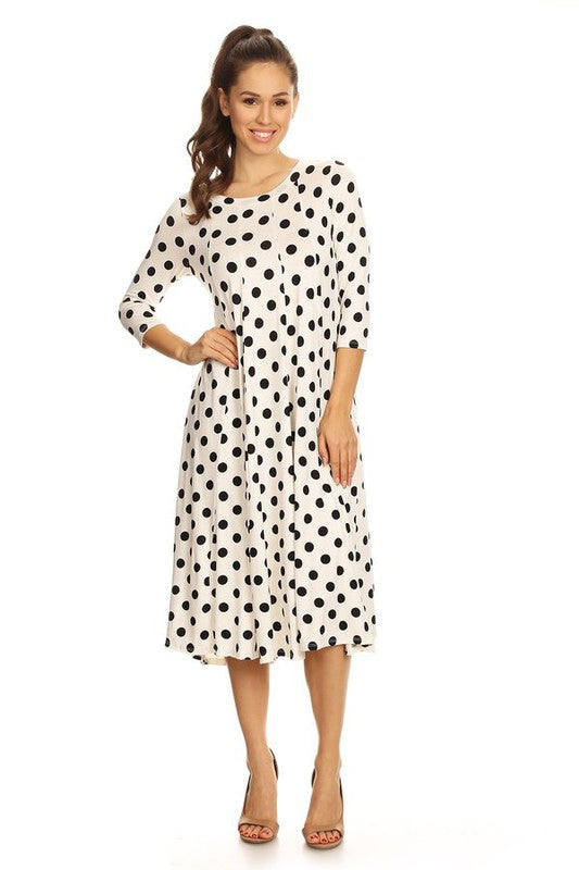 Woman wearing a paneled polka dot A-line midi dress with ¾ sleeves.