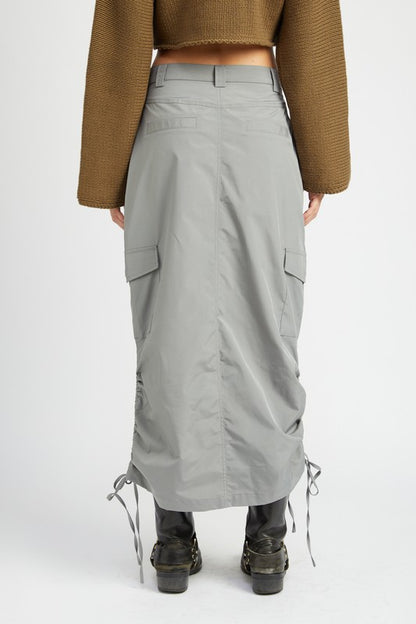 Person wearing a long gray skirt with a plain background
