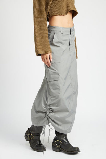 Person wearing gray cargo skirt and black boots on a white background