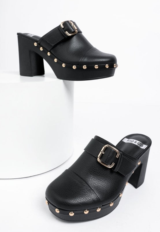 Black platform clogs with gold studs and buckles on a white background