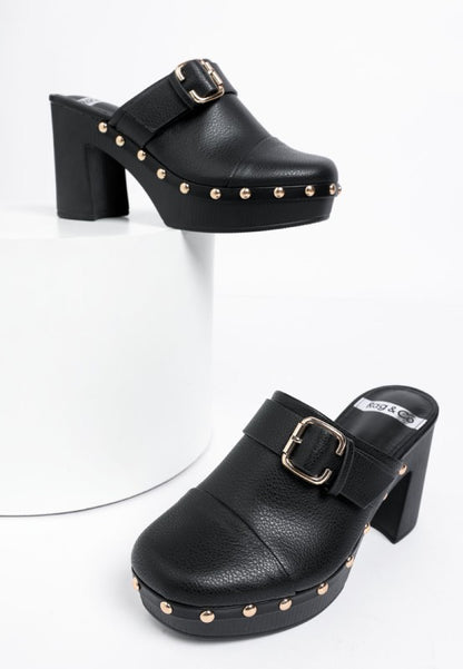 Black platform clogs with gold studs and buckles on a white background
