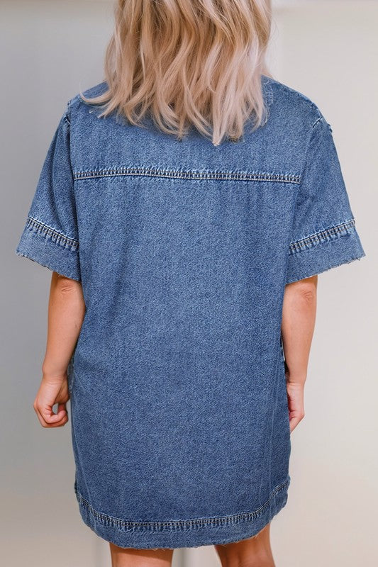 a woman wearing a denim mini dress. The dress has short sleeves, a collared neckline, and pockets.