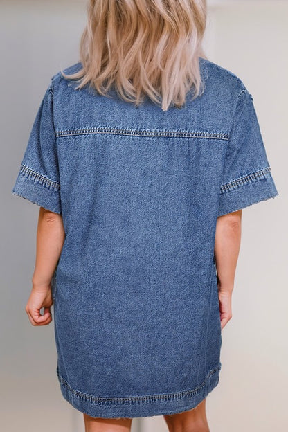 a woman wearing a denim mini dress. The dress has short sleeves, a collared neckline, and pockets.