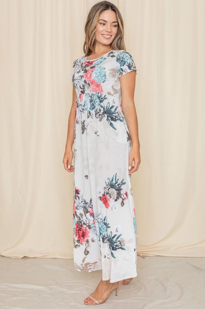 A woman posing in a short sleeve floral maxi gown. 